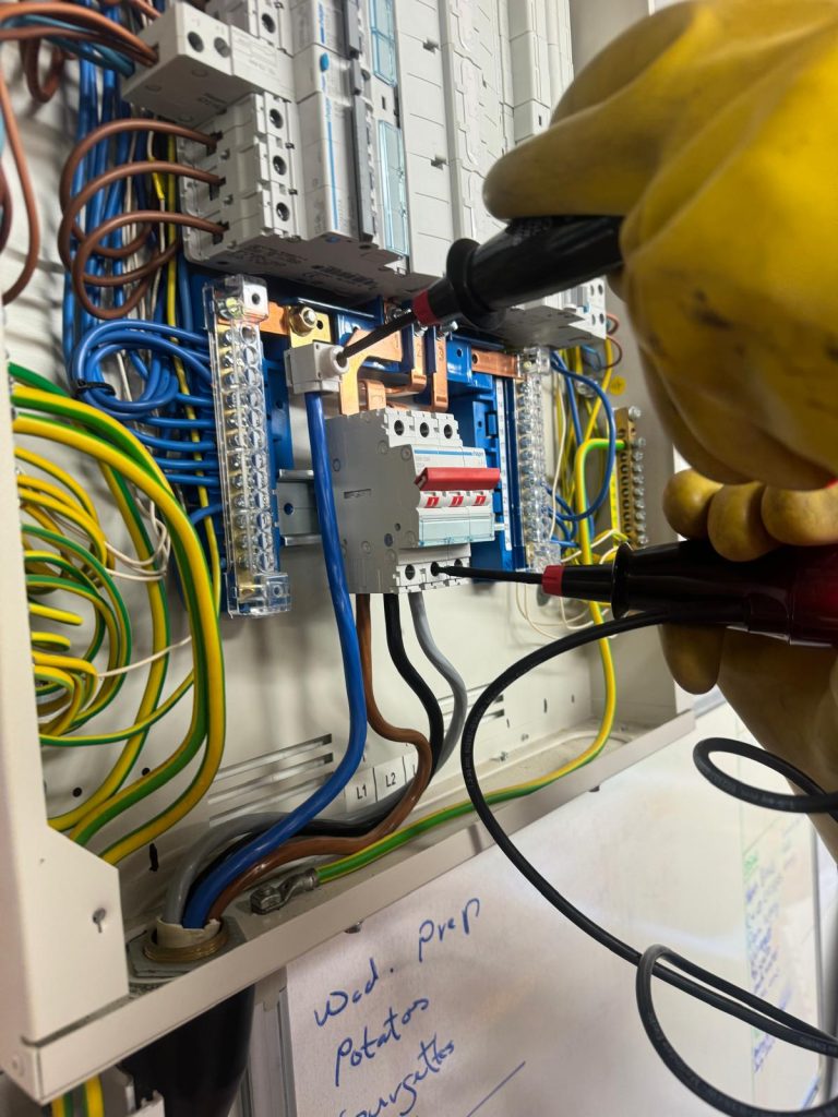 Electrician carrying out electrical testing on a consumer unit during an EICR